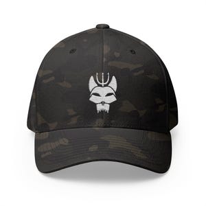 May include: Black camouflage baseball cap with a white embroidered emblem of a stylized skull with a trident. The cap has a curved brim and a structured fit, suitable for various outdoor activities.