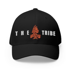 May include: Black baseball cap with the text "THE TRIBE" in white block letters. An orange Native American chief graphic is centered between the words. The cap has a curved brim and a structured fit.