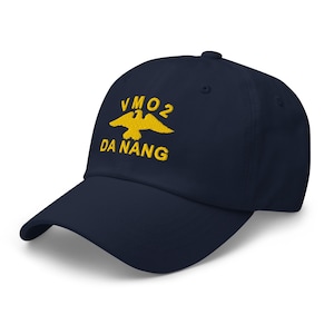 Op de afbeelding: Marineblauwe baseballcap met gele borduursels. De tekst "VMO 2 DA NANG" en een gele adelaar sieren de voorkant. De cap heeft een gebogen klep en een gestructureerde pasvorm.