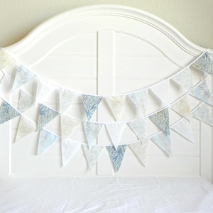 May include: A white headboard with a blue and white patterned fabric bunting draped across it.