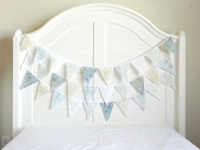 May include: A white headboard with a blue and white patterned fabric bunting draped across it.