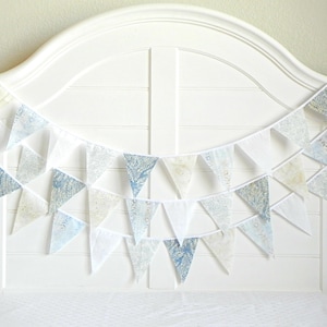 May include: A white headboard with a blue and white patterned fabric bunting hanging across it. The bunting is made of triangular flags with a white background and a blue pattern.