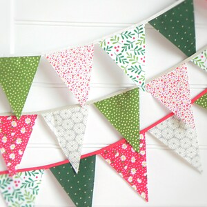 Pode incluir: Uma bandeirola festiva com bandeiras triangulares verdes, vermelhas e brancas. Cada bandeira tem um padr&atilde;o diferente, incluindo bolinhas, desenhos florais e folhas.
