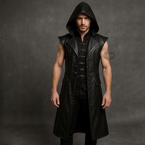 May include: A black hooded leather vest with a long, flowing design. The vest features a button-up front and two pockets. The model is wearing a black shirt underneath. The vest is sleeveless and has a hood.