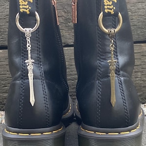 May include: A white ceramic mug with a black handle and the text "But First, Coffee" in a black, handwritten-style font. The mug is on a white surface.