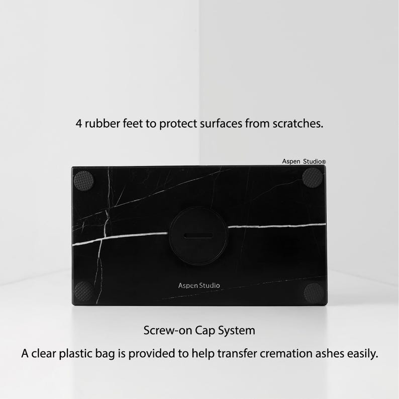 May include: Black marble cremation urn with white veining, featuring a screw-on cap system. The urn has four rubber feet to protect surfaces. The text "Aspen Studio" is visible. A clear plastic bag is provided to help transfer cremation ashes easily.
