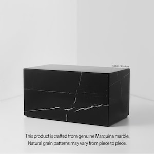 May include: A rectangular black marble box with white veining. The product is crafted from genuine Marquina marble. The text "Aspen Studio&reg;" is in the upper right corner. The text "This product is crafted from genuine Marquina marble. Natural grain patterns may vary from piece to piece." is at the bottom.