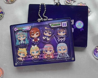 May include: A rectangular, dark blue keychain featuring nine cartoon characters. The keychain has a silver chain and a dark blue backing. The characters are in various colors, and the word "PERFECT" is visible.