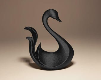 May include: A black swan figurine with a textured surface. The swan has a long, curved neck and a graceful, flowing tail. The figurine is set against a neutral background, highlighting its elegant form.