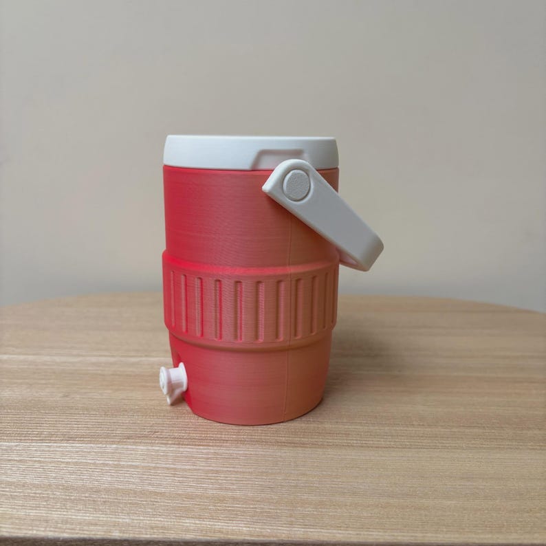 May include: A small, red and white cooler with a white handle and a spigot. The cooler has a ribbed design around the middle and a white lid. The cooler is designed to hold liquids and keep them cool.