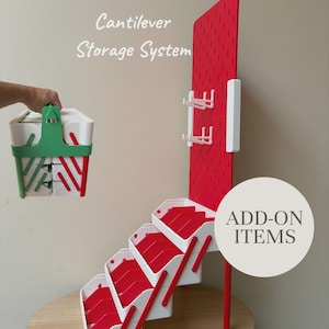 May include: A cantilever storage system featuring a red pegboard with white hooks and a white and red tiered tray structure. A separate white and green portable storage unit is shown. Text reads Cantilever Storage System and ADD-ON ITEMS.
