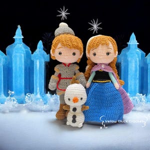 May include: Crocheted dolls of characters from the animated film "Frozen", including Anna, Kristoff, and Olaf. Anna wears a blue dress with a black bodice and purple cape. Kristoff is in a gray outfit, and Olaf is a white snowman.