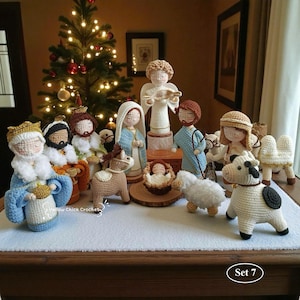 May include: A crocheted nativity scene featuring figures such as the Three Wise Men, Mary, Joseph, an angel, baby Jesus, and animals. The figures are in various colours, including blue, white, brown, and gold. A Christmas tree is in the background.