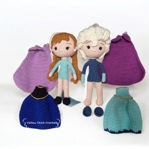 Pu&ograve; includere: Bambole all'uncinetto di due personaggi, una con capelli rossicci e l'altra con capelli bianchi, con abiti blu. Sono presenti anche mantelli e vestiti all'uncinetto in tonalit&agrave; blu e viola. Il testo "Yellow Chick Crochet" &egrave; visibile.
