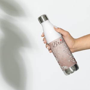 May include: A white stainless steel water bottle with a floral design and the word "Bride" in black script with a red heart.