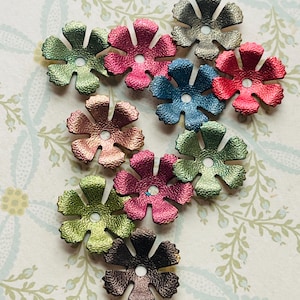 May include: Assortment of ten metallic flower embellishments in various colors, including green, pink, blue, and brown. Each flower has a scalloped edge and a white center.