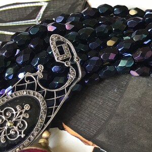 May include: A silver filigree pendant with a black oval cameo and a row of iridescent black beads.
