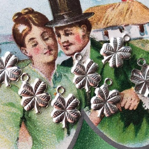 May include: Seven silver four-leaf clover charms with a loop at the top for attaching to jewelry or other crafts.