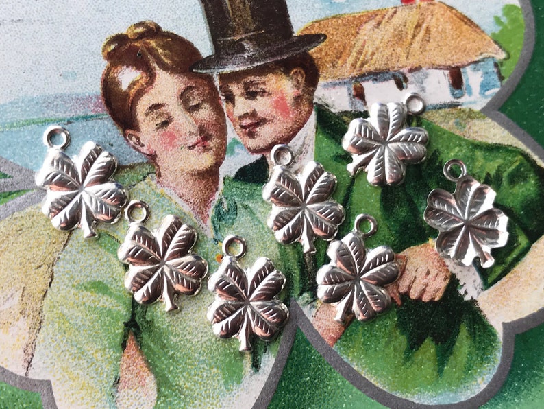 May include: Seven silver four-leaf clover charms with a loop at the top for attaching to jewelry or other crafts.