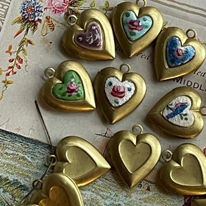 May include: A collection of gold heart-shaped locket charms with painted floral designs. The lockets have a hinged opening and are perfect for adding a personal touch to jewelry.