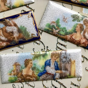 May include: Four rectangular ceramic tiles with painted scenes of couples in a garden setting. The tiles have a white background with a silver shimmer effect. The scenes are painted in muted colors with a romantic theme.