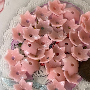 Peut inclure: Un ensemble de boutons en plastique rose en forme de fleur. Les boutons ont une forme d'&eacute;toile &agrave; cinq branches avec un trou au centre.
