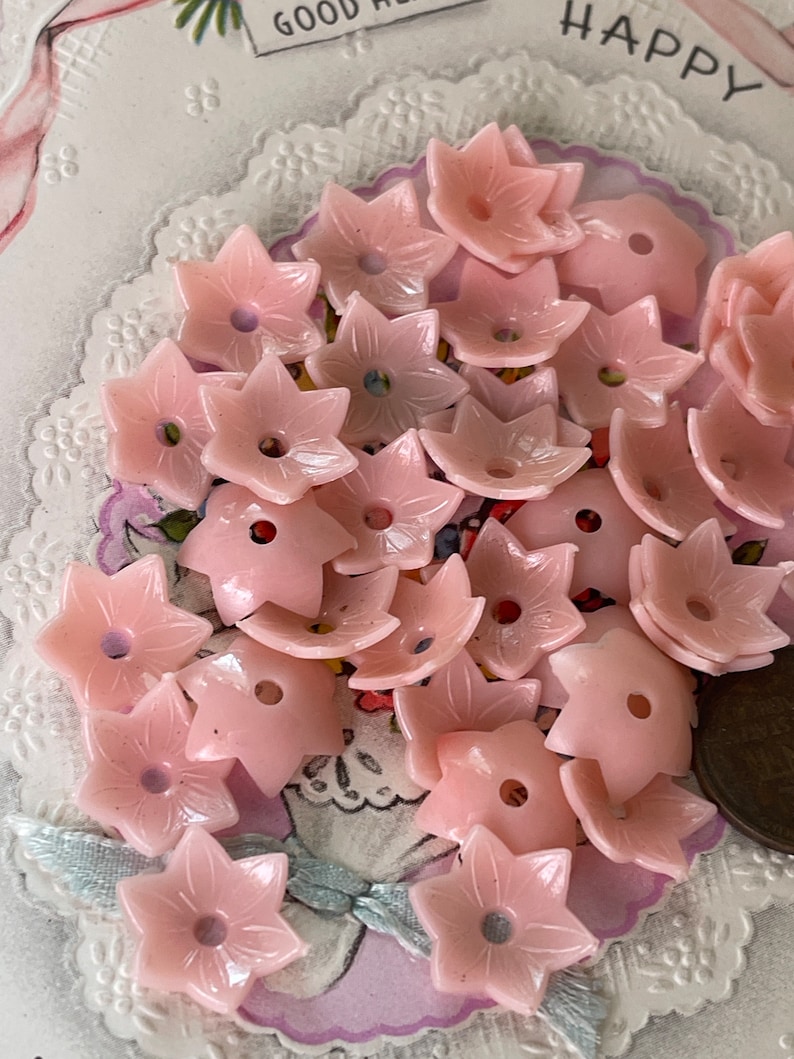 Peut inclure: Un ensemble de boutons en plastique rose en forme de fleur. Les boutons ont une forme d'&eacute;toile &agrave; cinq branches avec un trou au centre.