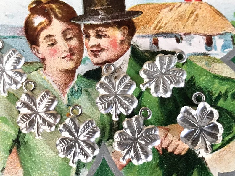 May include: Seven silver four-leaf clover charms with a textured surface. The charms have a loop at the top for attaching to a necklace or bracelet.