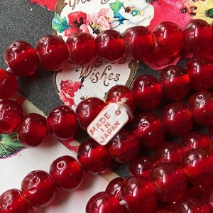 May include: A strand of red glass beads with a tag that reads "Made in Japan".