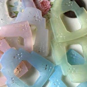 May include: Assortment of pastel-colored glass buttons with a starburst design. The buttons are translucent and have a slightly frosted finish.