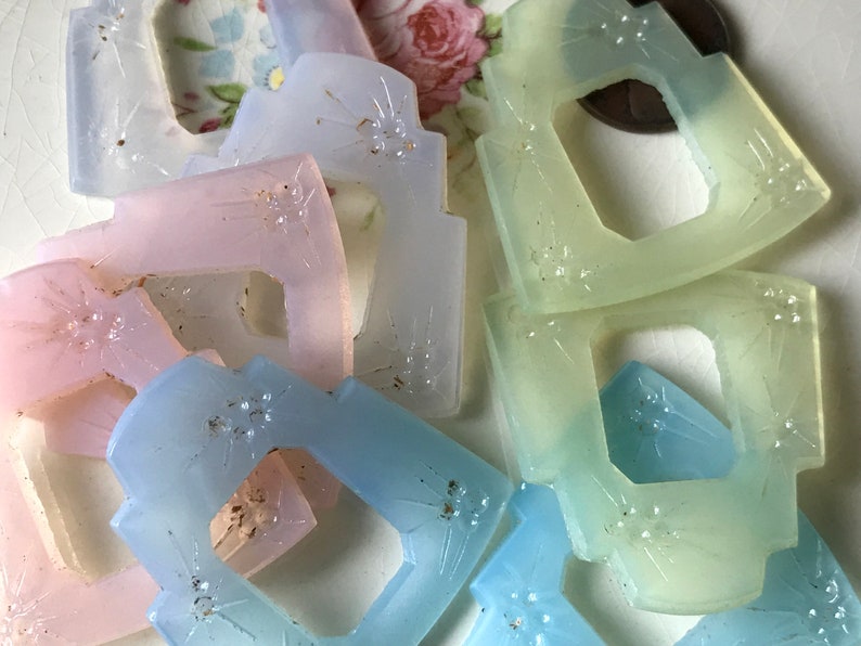 May include: Assortment of pastel-colored glass buttons with a starburst design. The buttons are translucent and have a slightly frosted finish.