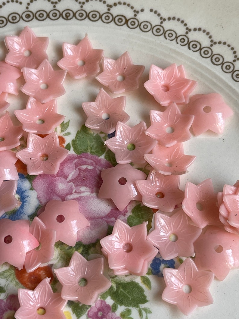 Peut inclure: Un ensemble de boutons en plastique rose en forme de fleur. Les boutons ont une forme d'&eacute;toile &agrave; cinq branches avec un trou au centre.