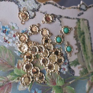 May include: A collection of gold-toned metal connector charms with a rope-like design and a round centre. There are also several green glass beads with a round shape.