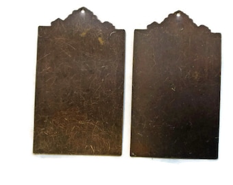 May include: Two antique brass plaques with ornate edges. The plaques are rectangular and have a worn, aged appearance.