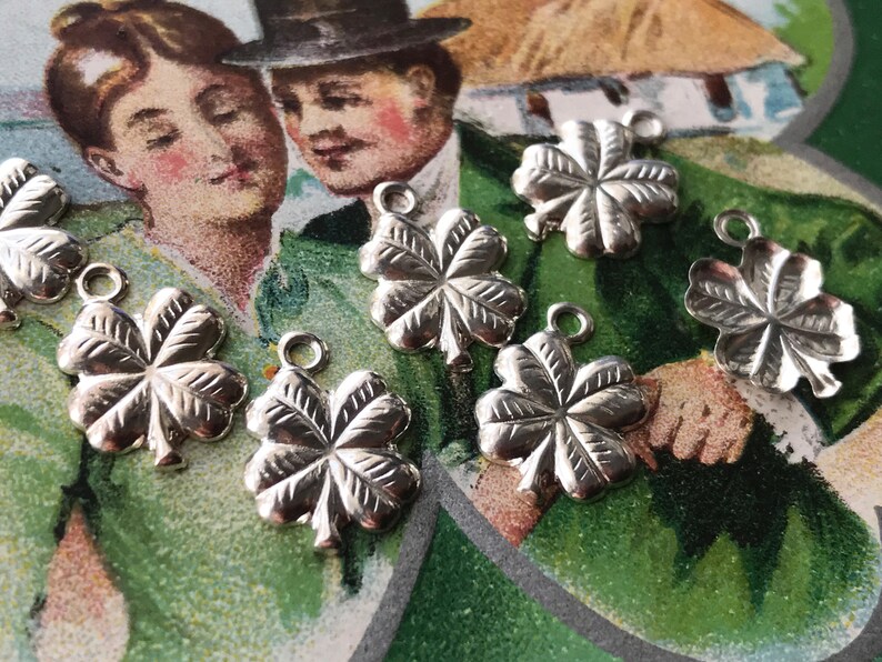 May include: Seven silver four-leaf clover charms with a textured finish. The charms have a loop at the top for attaching to a necklace or bracelet.