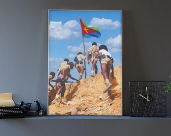 Puede incluir: Una impresión enmarcada representa a un grupo de personas subiendo una colina rocosa, con una persona sosteniendo una bandera con colores rojo, verde, amarillo y azul contra un cielo azul. La imagen se muestra en una pared gris.