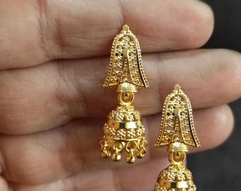 May include: A pair of gold-colored bell-shaped earrings. The earrings have a detailed filigree design on the top and a textured, rounded bottom. Small, dangling accents hang from the bottom of each earring.