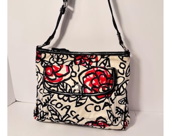 Bolsa transversal Coach Poppy Y2K com estampa floral grafite, nas cores preto, vermelho e creme, com detalhes em cetim envernizado.