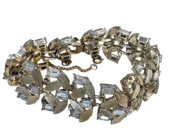 Pulseira vintage François em tom dourado com elos em formato de folha e strass transparente em formato de baguete. Assinada.