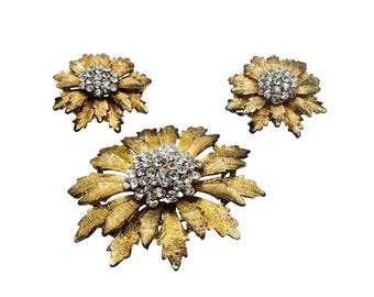 Conjunto floral dos anos 1950 composto por broche de flor com strass em tom dourado e brincos de pressão.
