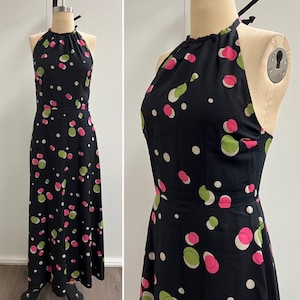 May include: A black halter-neck maxi dress with a pattern of pink, green, and white polka dots. The dress has a fitted bodice and a flowing skirt. The dress is displayed on a mannequin.