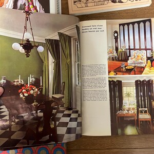 May include: A magazine spread featuring two interior design photos. The first photo shows a dining room with a green wall, a black and white checkered floor, and a chandelier with three white globes. The second photo shows a living room with a large window, a black and white patterned sofa, and a black screen.