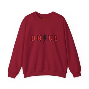 May include: A maroon sweatshirt with a black lightning bolt and the word "OBSCD" in red letters.