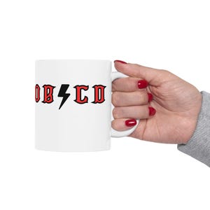 May include: White ceramic mug with a red and black graphic that says "OBSCD" with a lightning bolt in between the letters.