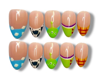 May include: Set of ten almond-shaped false nails with a nude base and various designs. Designs include blue sky with white clouds, black and white cow print, green alien, green and purple stripes, and red and yellow plaid.