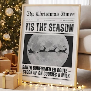 May include: A framed Christmas-themed newspaper print with the headline "TIS THE SEASON" and an illustration of Santa's sleigh. The print is next to a decorated Christmas tree with wrapped gifts and string lights.