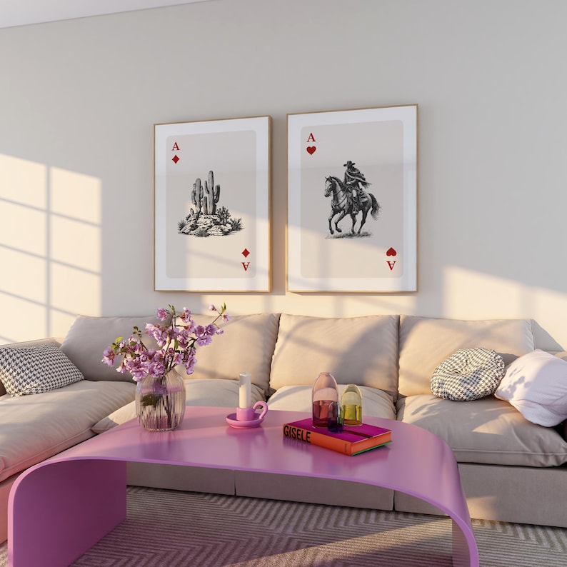 K&ouml;nnte beinhalten: Zwei gerahmte Kunstdrucke, die Spielkarten-Asse darstellen. Einer zeigt einen Kaktus, der andere einen Cowboy auf einem Pferd. Sie h&auml;ngen &uuml;ber einem rosa Couchtisch mit einer Blumenvase und dekorativen Gegenst&auml;nden.