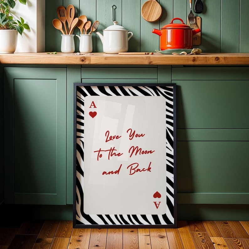 May include: Framed art print featuring a playing card design with the Ace of Hearts. The print has a zebra stripe border and the text "Love You to the Moon and Back" in red script. The artwork is displayed in a kitchen setting.