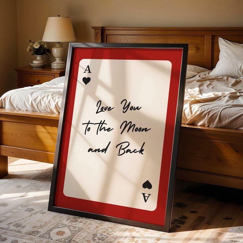 May include: A framed print resembling an Ace of Hearts playing card. The card has a white center with the text "Love You to the Moon and Back" in black script. The frame is black, and the matting is red.