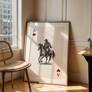 K&ouml;nnte beinhalten: Gerahmter Kunstdruck der Herz-Ass-Spielkarte. Die Karte zeigt eine Schwarz-Wei&szlig;-Illustration eines Cowboys auf einem Pferd. Die Karte hat ein rotes Herzsymbol und den Buchstaben "A" in den oberen und unteren Ecken.
